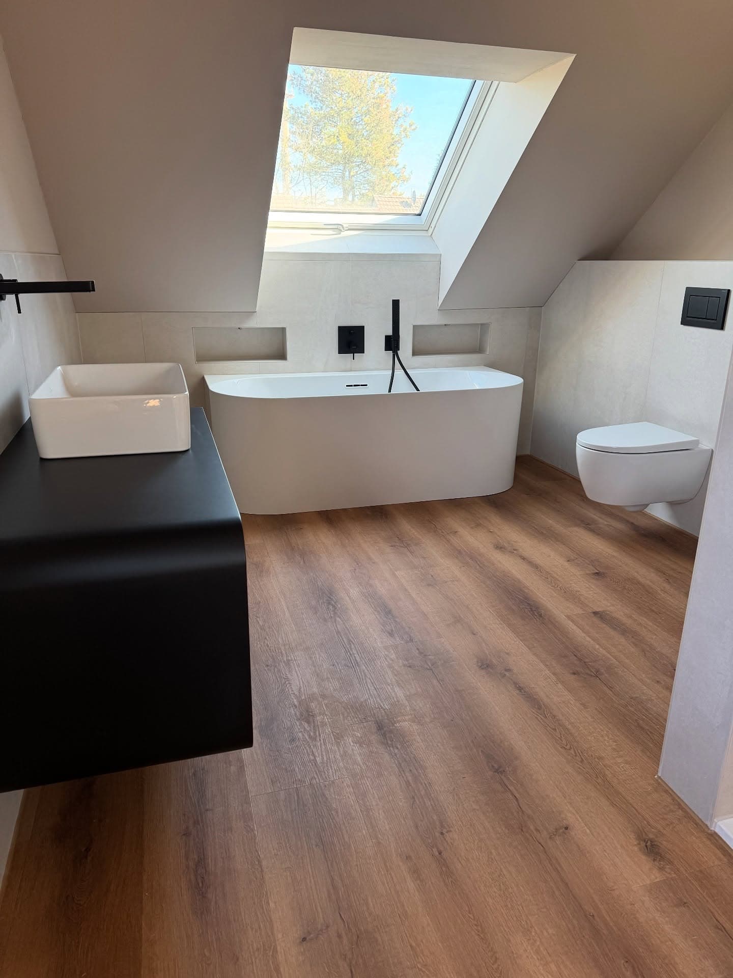 Freistehende Badewanne mit Dachflächenfenster und dunklen Armaturen