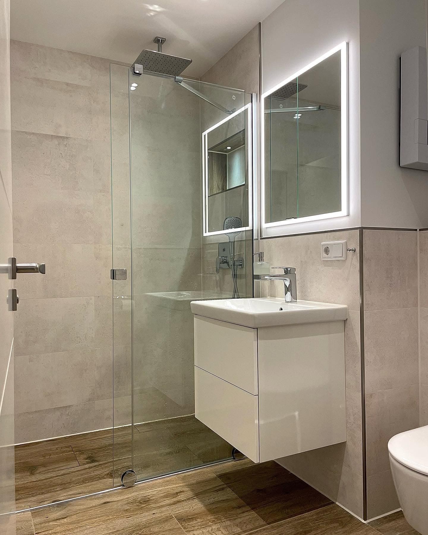 Helles Badezimmer mit bodengleicher Glasdusche und wandhängendem Waschtisch